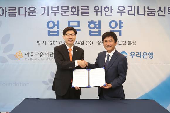 ▲ 24일 서울 중구 우리은행 본점에서 진행된 ‘우리은행-아름다운재단과 기부문화 확산을 위한 우리나눔신탁 업무협약’에서 이광구 우리은행장(왼쪽)이 박종문 아름다운재단 이사장(오른쪽)과 업무협약을 체결한 뒤 악수를 하고 있다.(사진제공=우리은행)