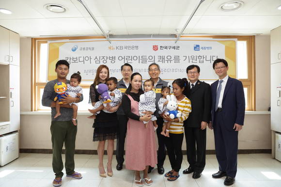 ▲KB국민은행은 31일, 부천 세종병원을 찾아가 ‘캄보디아 심장병 어린이 의료 지원’사업을 통해 국내에서 수술을 마치고 회복중인 어린이들을 격려했다. 뒷줄 왼쪽부터 세번째 진웅섭 금융감독원장, 왼쪽부터 네번째 윤종규 KB국민은행장, 왼쪽부터 다섯번째 신재국 구세군사무총장, 왼쪽부터 여섯번째 박진식 부천세종병원 이사장, 왼쪽부터 두번째 손연재 KB금융그룹 홍보모델.(사진제공=KB국민은행)