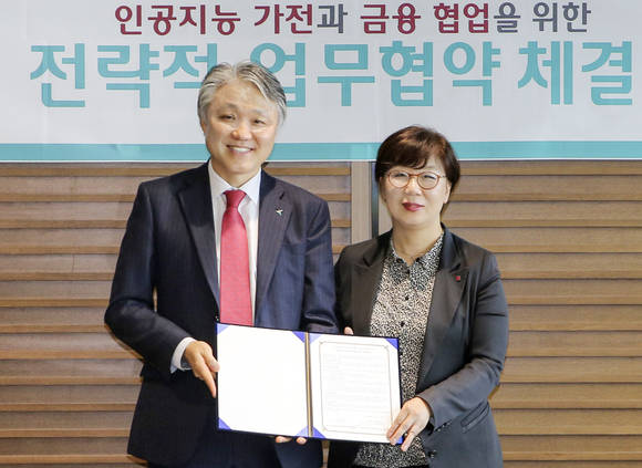 ▲KEB하나은행은 9일 오후 서울시 중구 본점에서 LG전자와 인공지능 가전 기반의 신개념 금융 상품 및 서비스를 공동 개발하기 위한 전략적 업무협약을 체결했다고 10일 밝혔다. 협약시에 참석한 한준성 KEB하나은행 미래금융그룹 부행장(사진 왼쪽)과 류혜정 LG전자 H&A스마트솔루션사업부 전무(사진 오른쪽)가 협약식 종료 후 기념촬영을 하고 있다.(사진제공=KEB하나은행)