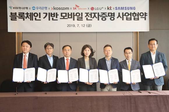 ▲한준성 KEB하나은행 미래금융그룹 부행장(왼쪽부터), 황원철 우리은행 디지털금융그룹장, 김계영 코스콤 미래성장본부장, 오세현 SK텔레콤 블록체인/인증유닛장, 이상민 LG유플러스 FC부문장, 서영일 KT 블록체인비즈센터장, 김주완 삼성전자 서비스기획그룹장 등 블록체인 기반 모바일 전자증명 사업 참여사 관계자들이 지난 12일 서울 중구 더플라자호텔에서 업무협약을 체결한 뒤 기념촬영을 하고 있다.