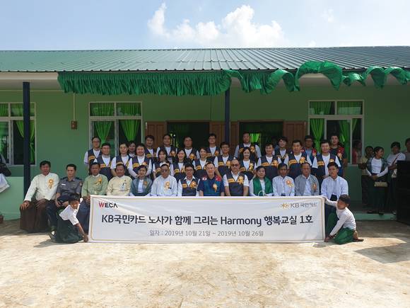 ▲10월 24일 미얀마 양곤 ‘쉐비다 제17초∙중학교’에서 열린 다목적 교실 개소식에서 이경진 전국사무금융서비스노동조합 KB국민카드지부장(앞줄 왼쪽에서 7번째)과 우모쪼아웅 쉐비다 시장(앞줄 왼쪽에서 6번째) 등 현지 관계자들과 KB국민카드 노사 공동 해외 봉사단이 기념 촬영을 하고 있다.(사진제공=KB국민카드)