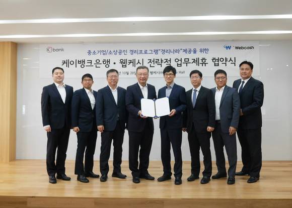 ▲심성훈 케이뱅크 은행장(왼쪽 네번째)과 윤완수 웹케시 대표(다섯번째) 등 두 회사 관계자들이 28일 전략적 업무제휴를 맺은 뒤 기념촬영을 하고 있다. / 사진=웹케시