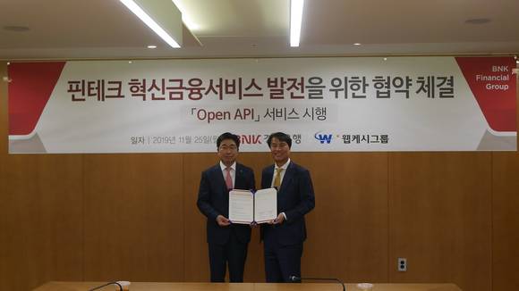 ▲황윤철 BNK경남은행장(왼쪽)과 석창규 웹케시그룹 회장이 25일 BNK경남은행 본점에서 업무협약을 체결한 뒤 기념촬영을 하고 있다. / 사진=웹케시그룹