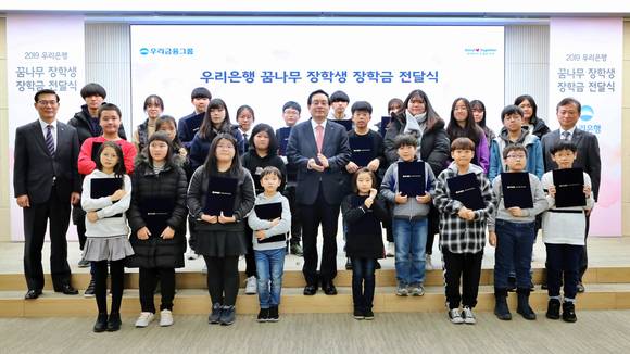 ▲우리금융그룹은 서울시 중구 우리은행 본점에서 '우리은행 꿈나무 장학생 장학금 전달식'을 갖고 지역아동센터 장학생 74명에게 장학금을 전달했다. 자리에 참석한 손태승 우리금융그룹 회장 겸 우리은행장(가운데)이 장학생 대표 30명 및 우리금융그룹 주요관계자와 기념촬영을 하고 있다.(사진제공=우리은행)