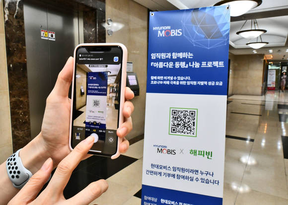 ▲현대모비스 직원이 모바일 QR코드 방식으로 자발적 기부 캠페인에 참여하고 있다. (사진제공-현대모비스)
