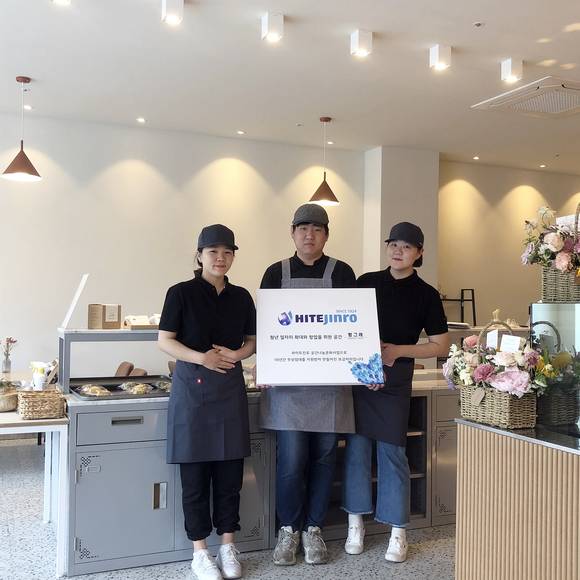 ▲하이트진로는 ‘청년창업 프로젝트’의 일환으로 마산 공장 인근 상가에 청년들이 직접 운영하는 베이커리 카페 '빵그레'를 오는 27일 오픈한다고 밝혔다. 프로젝트에 선발된 청년 3명이 베이커리 카페 '빵그레'에서 기념 사진을 촬영 하고 있다.(사진제공=하이트진로)