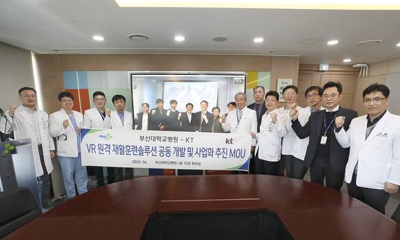 ▲김훈배 KT 커스터머신사업본부장(화면 속 왼쪽 네 번째), 이정주 부산대병원장(오른쪽 일곱 번째) 등 양 사 관계자들이 VR 원격 재활훈련 솔루션 공동개발 및 사업화 업무협약을 체결한 뒤 기념촬영을 하고 있다. / 사진=KT