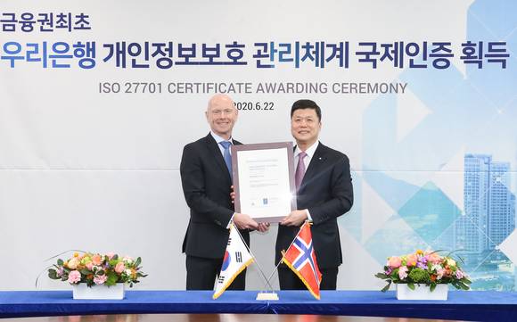 ▲우리은행은 국제표준 개인정보보호 인증인 ‘ISO27701’를 획득했다. 권광석 우리은행장(오른쪽)이 프로데 술베르그 주한 노르웨이 대사와 우리은행 본점에서 열린 인증서 수여식에서 기념촬영을 하고 있다.(사진제공=우리은행)