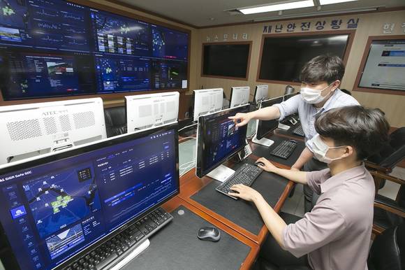 ▲KT는 한국판 뉴딜의 ‘SOC 디지털화’ 사업 협력을 위해 하남시에 구축한 ‘KT 기가세이프 SOC’ 솔루션을 15일 선보였다. KT와 하남시 직원들이 하남시청 관제실에서 시설물 안전상황을 모니터하고 있다. / 사진=KT