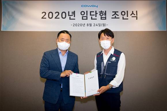 ▲이해선 코웨이 대표이사(왼쪽)와 이현철 전국가전통신서비스 노동조합 위원장이 지난 24일 서울시 중구 코웨이 본사에서 진행된 임단협 조인식에서 기념촬영을 하고 있다. / 사진=코웨이