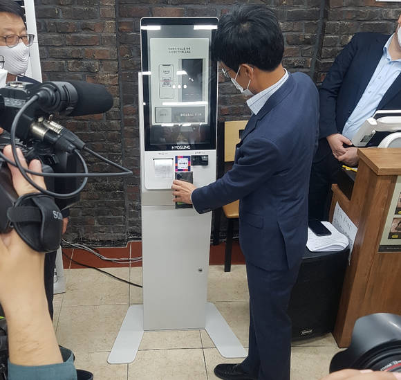 ▲윤완수 한국간편결제진흥원 이사장이 지난 28일 서울 관악구에서 열린 소상공인 키오스크 지원 사업 1호점 선정식에서 ‘제로페이’로 결제하고 있다. / 사진=한국간편결제진흥원