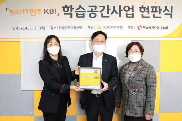 ▲(왼쪽부터) 추혜경 한별지역아동센터 센터장, 조용범 KB국민은행 ESG기획부장, 윤종선 부스러기사랑나눔회 상임이사가 현판식을 가진 후 기념촬영을 하고 있다. / 사진=KB국민은행