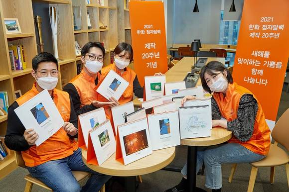 ▲한화 점자달력 제작 20주년을 맞아 한화봉사단 임직원들이 2001년 점자달력부터 시작해 지난 20년간 제작된 한화 점자달력을 소개하며 기념촬영을 하고 있다. / 사진=한화