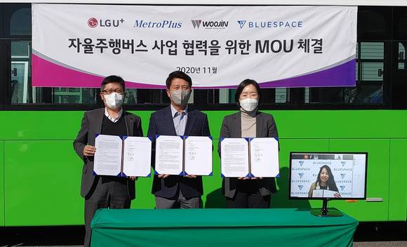 ▲(왼쪽부터) 조원석 LG유플러스 기업신사업그룹장, 김태호 메트로플러스 대표, 김정현 우진산전 사장, 크리스틴 문 블루스페이스 대표(모니터 화면)가 우진산전 충북 오창 공장에서 자율주행버스 사업 협력을 위한 양해각서를 체결한 뒤 기념촬영을 하고 있다. / 사진=LG유플러스