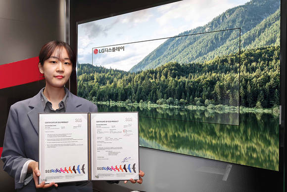 ▲LG디스플레이의 OLED TV 패널이 스위스 검사·인증기관 SGS로부터 친환경 제품 인증을 받았다. 사진은 LG디스플레이 직원이 OLED TV 앞에서 SGS 인증서를 들고 있는 모습 / 사진=LG디스플레이