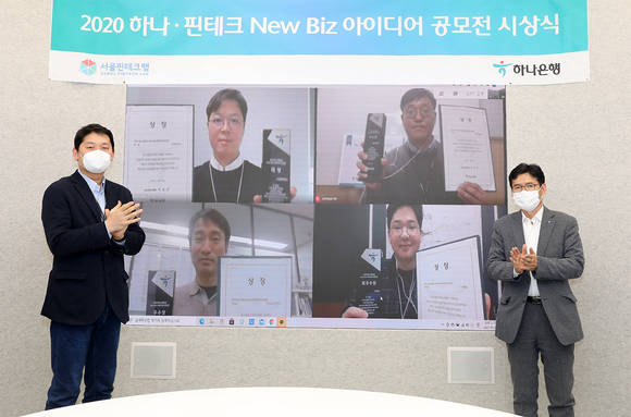 ▲권효용 하나은행 미래금융본부 셀장(오른쪽)과 고호현 서울 핀테크랩 센터장이 비대면으로 수상자들에게 상패와 상장을 전달하고 기념촬영을 하고 있다. / 사진=하나은행