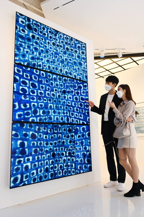 ▲LG전자가 서울 송파구 롯데백화점 에비뉴엘 월드타워점 6층 아트홀에서 열리고 있는 고 김환기 화백 작품 미디어 전시에 LED 사이니지, 올레드 TV 등을 설치했다. 모델들이 LG 올레드 TV를 이어 붙인 사이니지를 통해 작품을 감상하고 있다. / 사진=LG전자