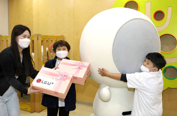 ▲4일 한국백혈병소아암협회를 방문한 홀맨과 LG유플러스 임직원이 소아암 환아들에게 선물을 전달하고 있다. / 사진=LG유플러스