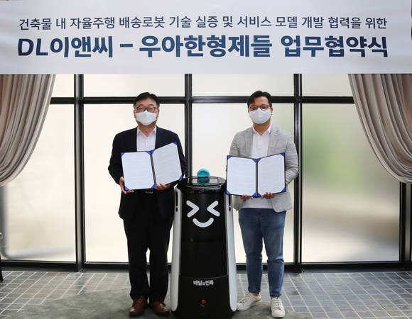 ▲나재현 DL이앤씨 주택사업본부 엔지니어링실장(왼쪽)과 김요섭 우아한형제들 로봇사업실장이 배송로봇 및 서비스모델 개발을 위한 업무협약식에서 기념촬영을 하고 있다 / 사진=DL이앤씨
