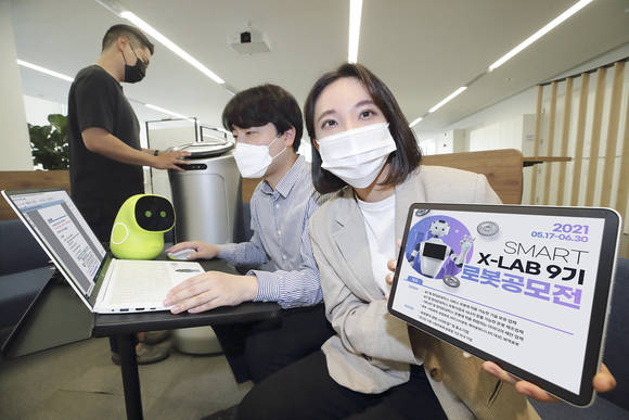 ▲KT가 17일부터 현대중공업그룹, 인천창조경제혁신센터와 함께 로봇 우수기업 선발 공모전을 진행한다. KT 직원들이 로봇 우수기업 선발 공모전 포스터를 확인하고 있다. / 사진=KT