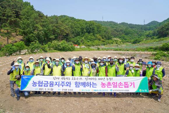 ▲배부열 NH농협금융지주 부사장(두번째 줄 왼쪽에서 여덟번째)과 임직원들이 봉사활동에 앞서 마을주민들과 기념촬영을 하고 있다. / 사진=NH농협금융지주