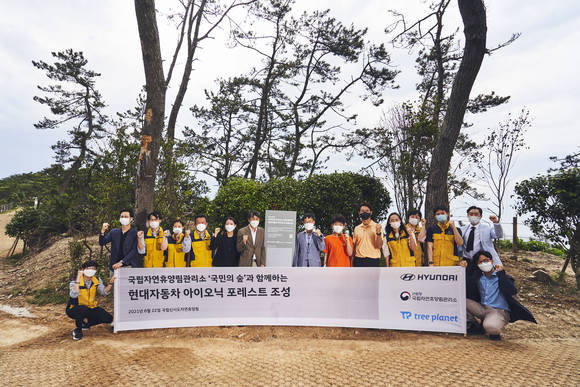 ▲최원준 현대자동차 CSV전략팀장(중앙 현판 왼쪽), 이영록 국립자연휴양림관리소장(중앙 현판 오른쪽), 트리플래닛 임직원 등 주요 관계자들과 신시도초등학교 학생 및 교사들이 기념촬영을 하고 있다. / 사진=현대자동차