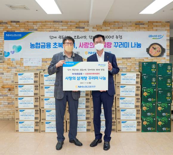 ▲배부열 NH농협금융지주 부사장(오른쪽)과 김영태 신당데이케어센터 센터장이 삼계탕 꾸러미 전달식 후 기념촬영을 하고 있다. / 사진=NH농협금융지주