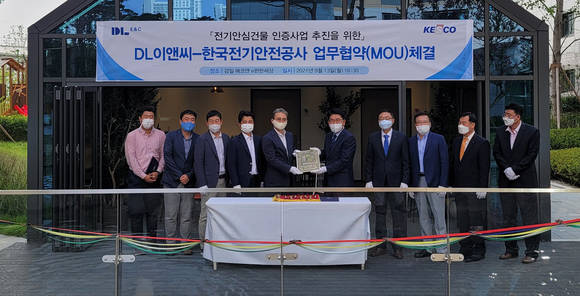 ▲권수영 DL이앤씨 주택사업본부장(왼쪽 다섯번째)과 김권중 한국전기안전공사 기술이사(여섯번째)가 경기도 하남 감일 에코앤 e편한세상 현장에서 전기 안심건물 인증 현판을 주고 받고 있다. / 사진=DL이앤씨