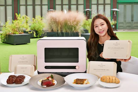 ▲삼성전자 모델이 서울신라호텔 영빈관 앞에서 신개념 조리기기 '비스포크 큐커'와 전용 밀키트 '신라 다이닝 앳 홈' 3종을 소개하고 있다. / 사진=삼성전자