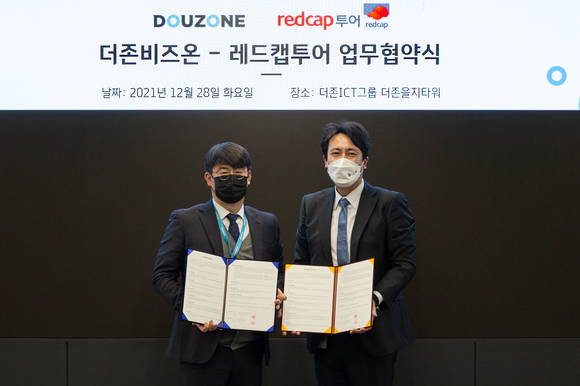 ▲전충재 더존비즈온 ERP사업부문 상무(왼쪽)와 이준호 레드캡투어 상무가 28일 서울 중구 더존을지타워에서 원스톱 비즈니스 솔루션 제공을 위한 ‘출장관리시스템 연동 업무협약’을 체결한 뒤 기념촬영을 하고 있다. / 사진=더존비즈온