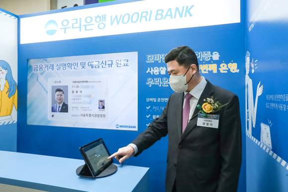 ▲권광석 우리은행장이 지난 27일 마포구 소재 서울서부면허시험장에서 열린 모바일 운전면허증 개통식 행사에 참석해 실명확인 서비스를 시연하고 있다. / 사진=우리은행