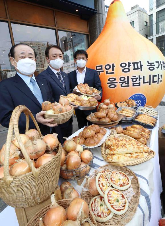 ▲지난 4월 6일 서울 서초구 파리바게뜨 강남서초점에서 열린 무안 양파 농가 돕기 ‘ESG 행복상생’ 행사에서 황재복 SPC그룹 대표(왼쪽 두 번째)와 권준학 농협은행장(첫 번째), 서삼석 국회의원(세 번째)이 ‘무안양파빵’을 들고 기념촬영을 하고 있다. / 사진=파리크라상