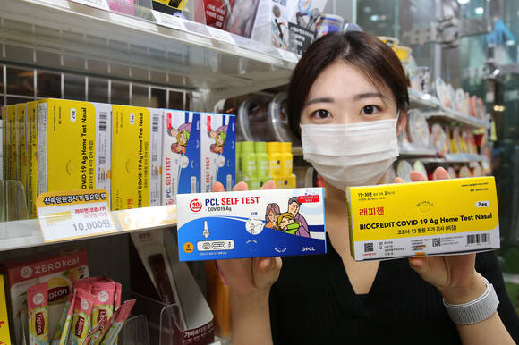 ▲GS25에서 모델이 PCL타액검사키트(왼쪽)와 래피젠자가검사키트를 들고 포즈를 취하고 있다. / 사진=GS25