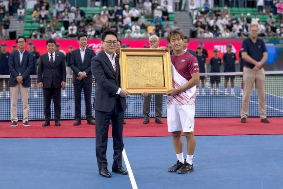 ▲장인상 코즈볼 회장이 지난 2일 ATP(남자프로테니스) 단식 우승자 니시오카 요시히토에게 김일태 화백의 금화 작품을 수여하고 있다. / 사진=코즈볼