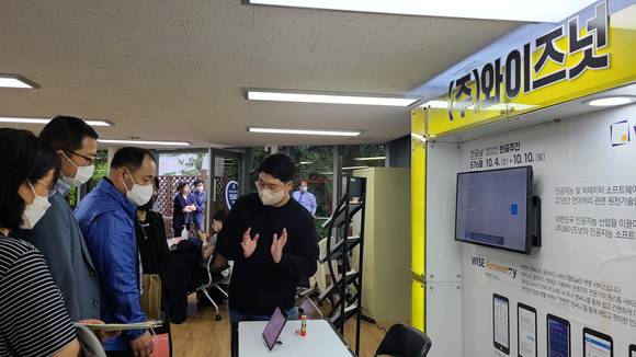 ▲‘2022 세계 한국어 한마당 – 한글·한국어 산업전’에서 와이즈넛 직원이 참관객에게 언어처리기술 기반의 AI 챗봇을 소개하고 있다. / 사진=와이즈넛