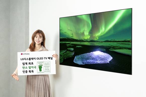 ▲LG디스플레이 OLED TV 패널이 디스플레이 업계 최초로 카본 트러스트 탄소발자국 인증을 획득했다고 밝혔다. LG디스플레이 모델이 카본 트러스트 인증서와 OLED TV 패널을 소개하고 있다. / 사진=LG디스플레이