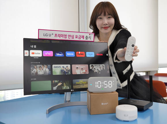 ▲LG유플러스 모델이 ‘프리미엄 안심 요금제’에서 제공되는 크롬캐스트, 기가와이파이 공유기, 와이파이메시, 스마트홈 스피커 ‘클로바 클락+3’를 소개하고 있다. / 사진=LG유플러스