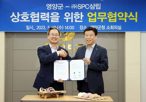 ▲박해만 SPC삼립 베이커리 부문 대표(오른쪽)와 오도창 영양군수가 지난 10일 경북 영양군청에서 진행한 ‘음식디미방 상화법 제품 개발 및 상품화를 위한 업무협약식’에서 기념촬영을 하고 있다. / 사진=SPC삼립