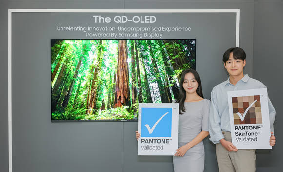 ▲삼성디스플레이 직원들이 TV용 QD-OLED 앞에서 팬톤 컬러 인증 및 팬톤 스킨톤 인증 로고를 들고 기념촬영을 하고 있다. / 사진=삼성디스플레이