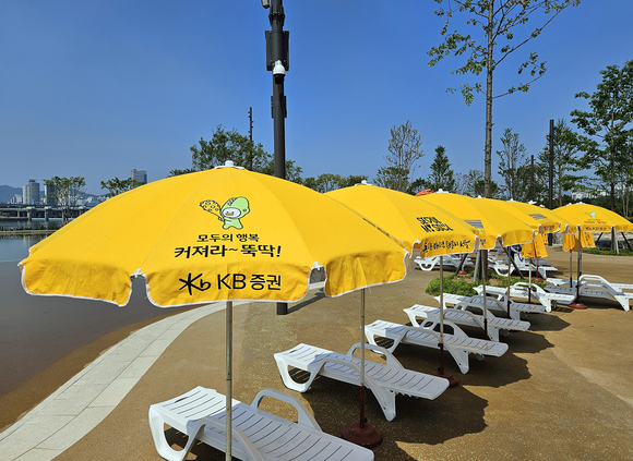 ▲KB증권이 지난 19일(수) 지역아동센터 이용 아동 300여명을 서울 잠실 물놀이장에 초청해 ‘약자와의 동행’ 행사를 진행한 가운데, 서울시 미래한강본부와 협력하여 파라솔 150개를 설치했다. / 사진=KB증권 KB증권, 잠실 물놀이장에서 여름맞이 약자와의 동행 진행