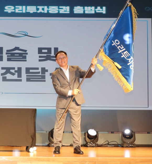 ▲남기천 우리투자증권 대표가 지난 1일 우리투자증권 출범식에서 회사기를 흔들고 있다. / 사진=우리투자증권