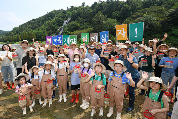 ▲현대모비스 임직원과 가족, 지역주민들이 23일 충북 진천군 초평면 미르숲 입구에서 미호종개를 방류하고 있다. / 사진=현대모비스 현대모비스, 1급 멸종위기종 미호종개 3000마리 방류