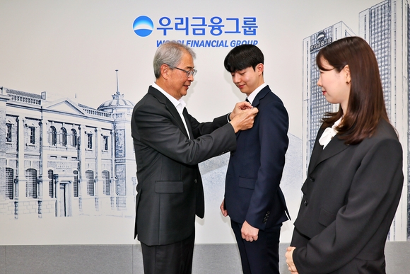 ▲임종룡 우리금융그룹 회장(왼쪽)이 그룹의 새 가족이 된 동양생명·ABL생명 직원에게 디지털 선도의 의미가 담긴 새로운 그룹 보조휘장을 달아주고 있다. / 사진=우리금융그룹 우리금융그룹, 보험사 자회사 편입 완료…종합금융그룹 포트폴리오 완성